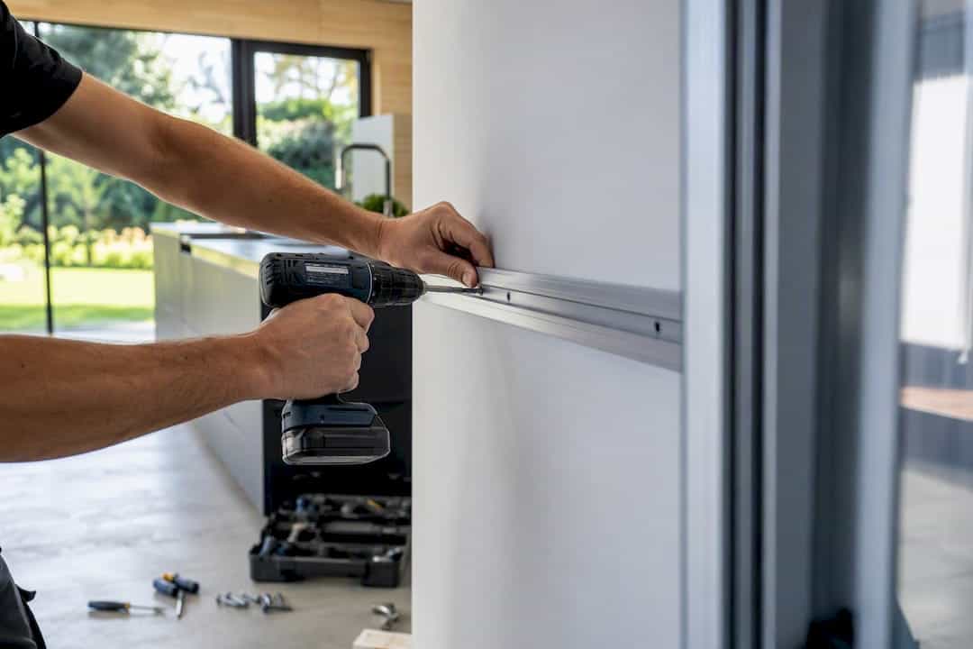 Hand die een aluminium schuifdeurbaan binnenshuis installeert