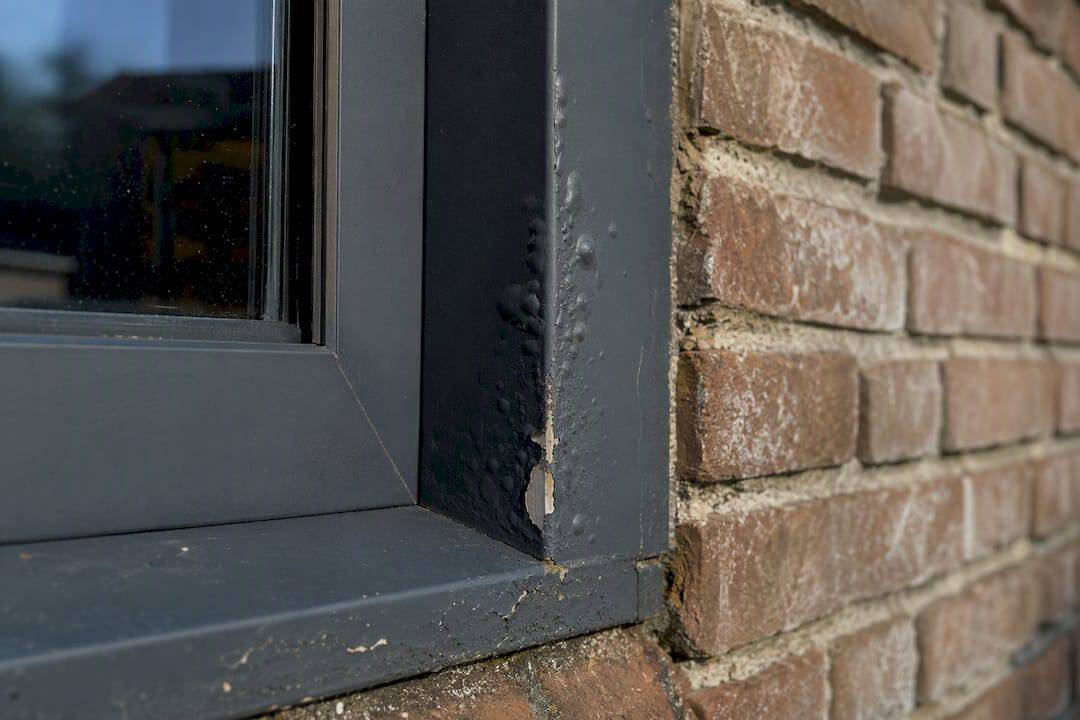 Close-up van een aluminium raamkozijn met osmoseblaren