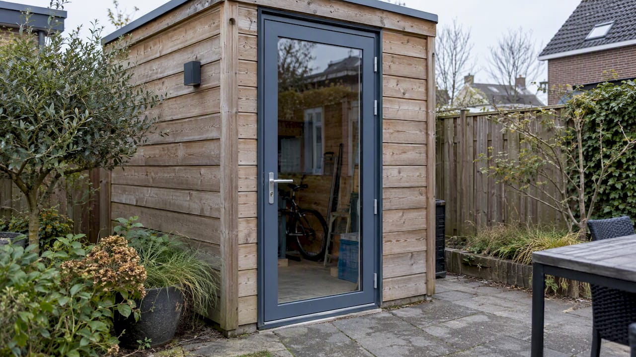 Blauwgrijze aluminium deur van het tuinhuis in een houten berging