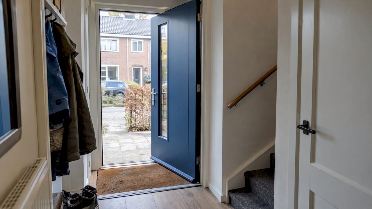 Blauwe aluminium buitendeur in een compacte hal